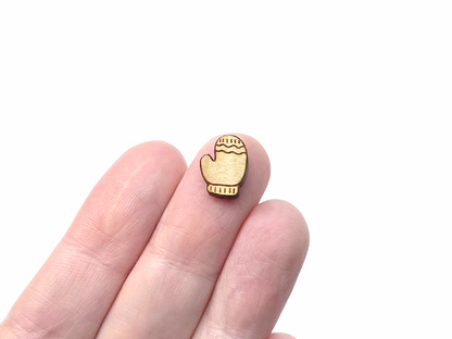 a person's hand holding a wood cabochon stud earring blanks cut and engraved to look like a winter mitten