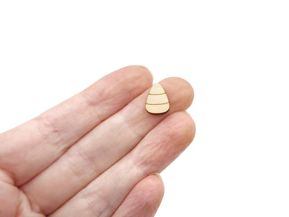 a person's hand holding a wooden cabochon stud earring blank cut and engraved to look like candy corn