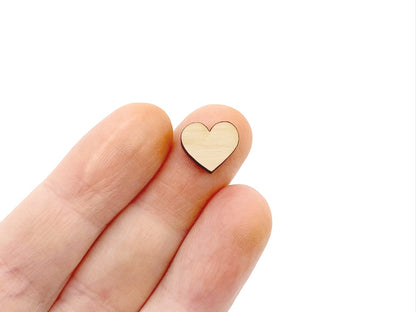 a hand holding a wood or acrylic cabochon earring blanks cut in the shape of a heart