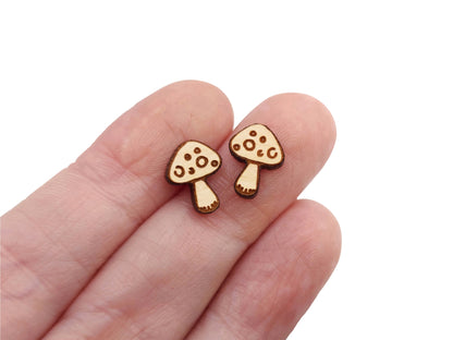 a hand holding a pair of small wooden earrings