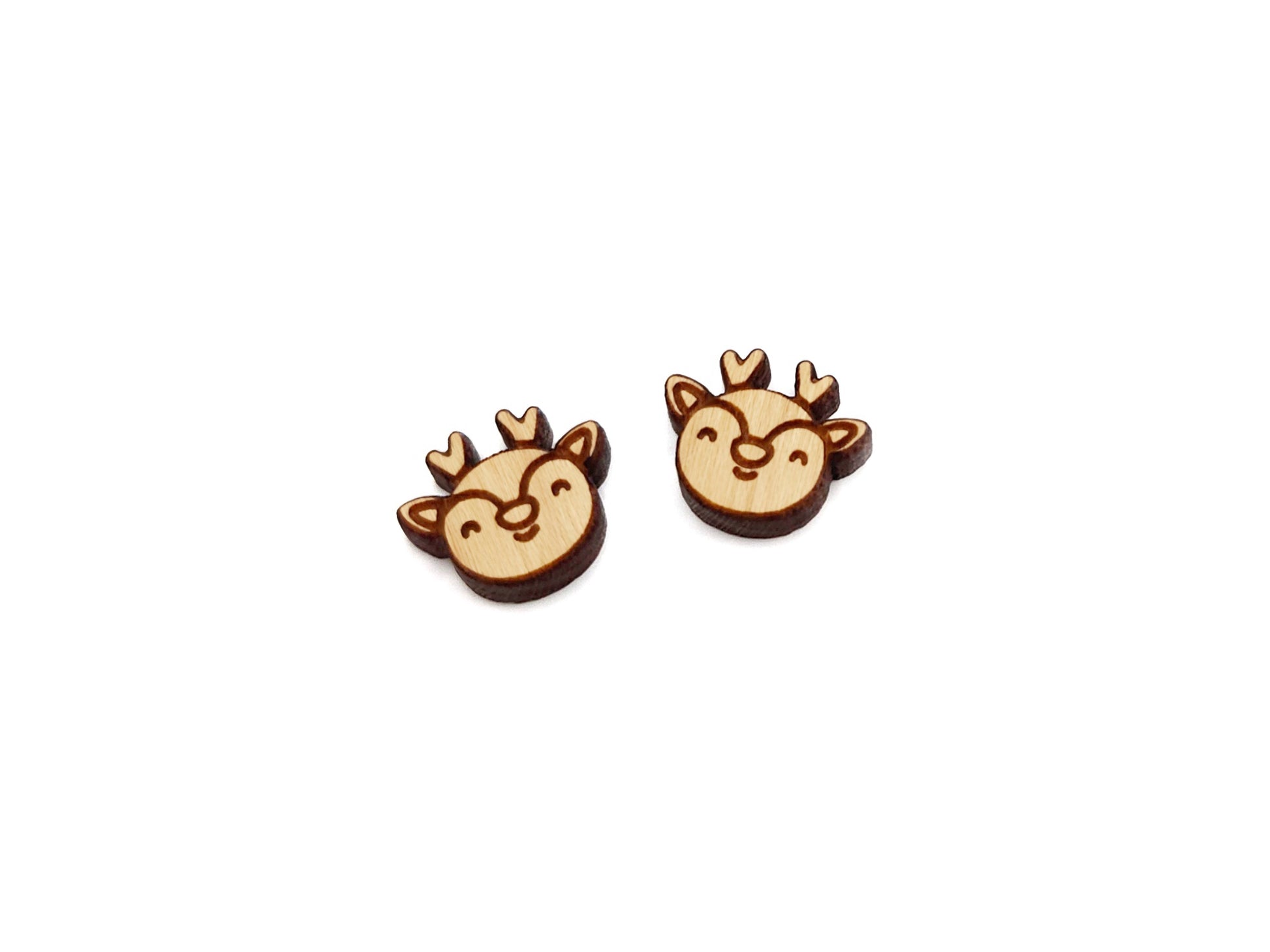 a pair of wooden cabochon stud earring blanks cut and engraved to look like a reindeer