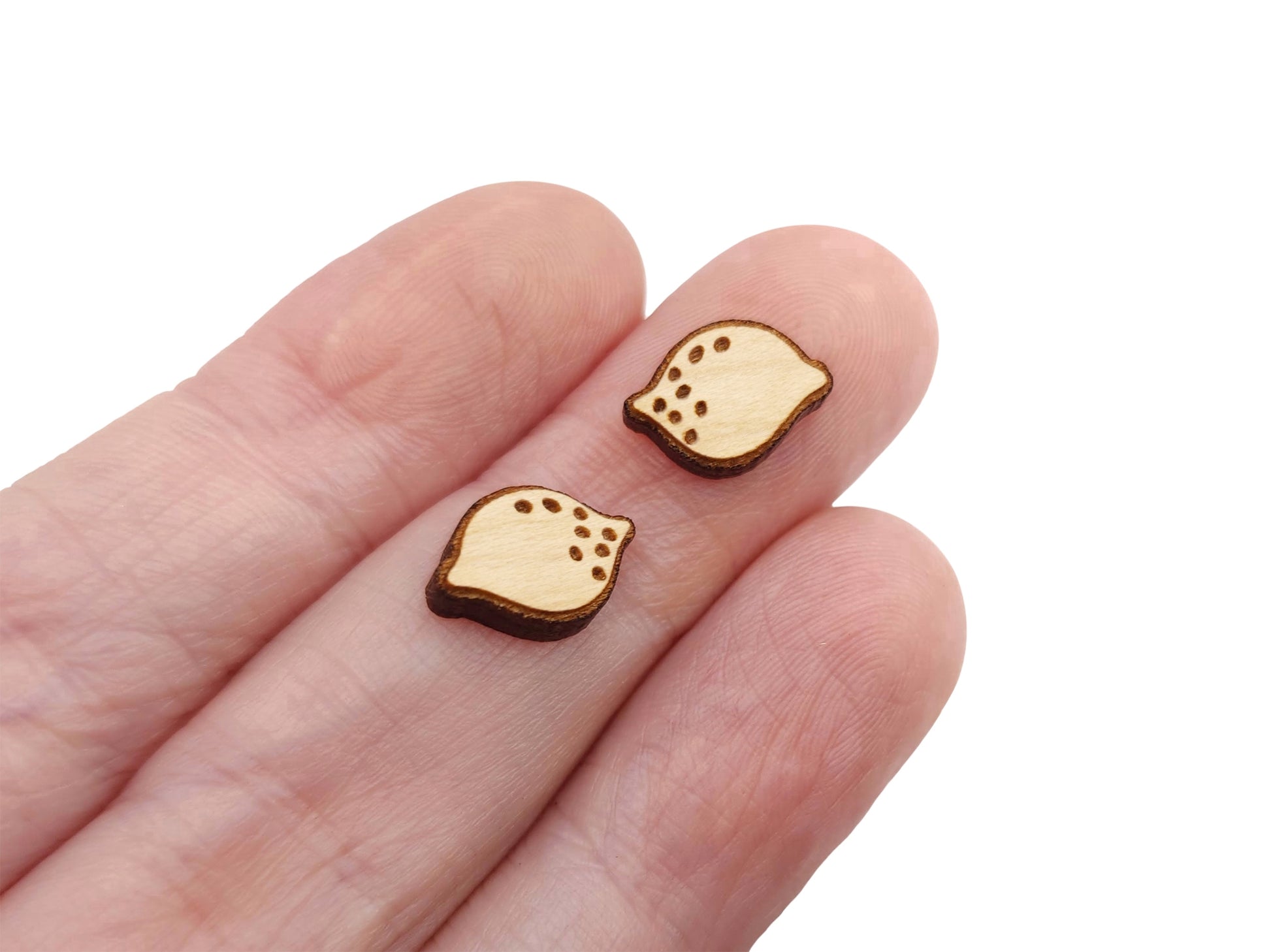 a hand holding a pair of wooden earrings