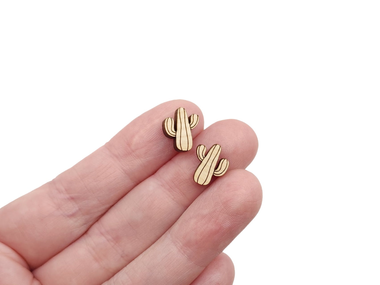a hand holding a pair of wooden cabochon stud earring blanks cut and engraved to look like a saguaro cactus