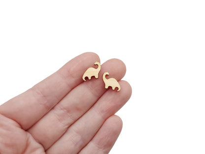 hand holding a pair of wooden cabochon earring blanks cut in the shape of a Brontosaurus dinosaur.