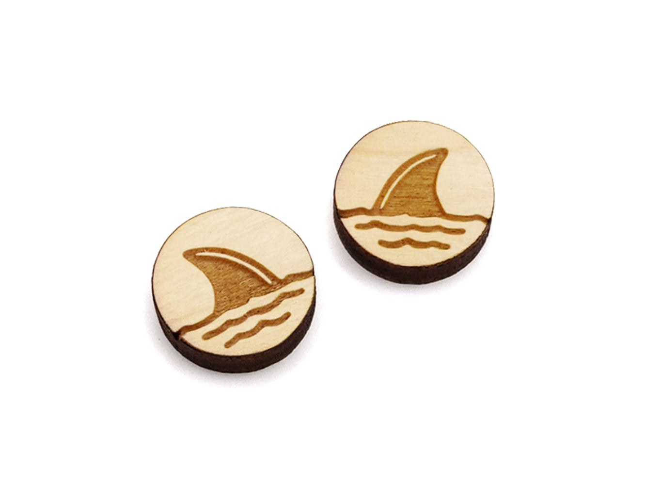 a pair of round wooden cabochon earring blanks engraved with a shark fin