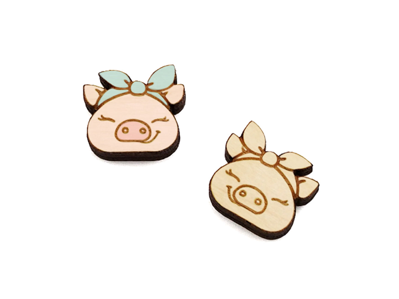 a pair of small wooden cabochon blanks for stud earrings, cut and engraved to look like a pig wearing a bandana