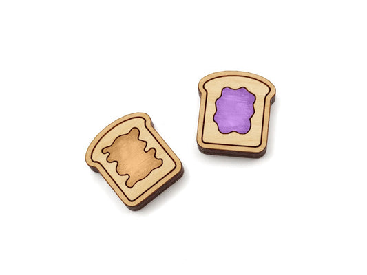 a pair of wooden cabochon stud earring blanks cut and engraved to look like pieces of bread with peanut butter and jelly