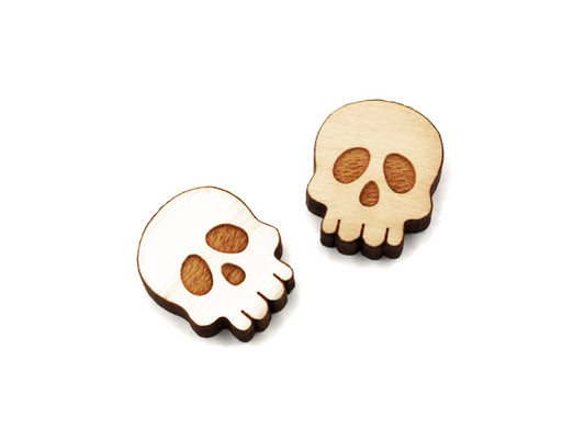 a pair of wooden flat-back cabochon blanks, engraved and cut to look like spooky skulls, one is painted