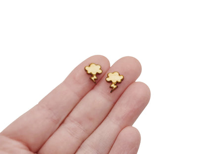 a hand holding a pair of gold earrings