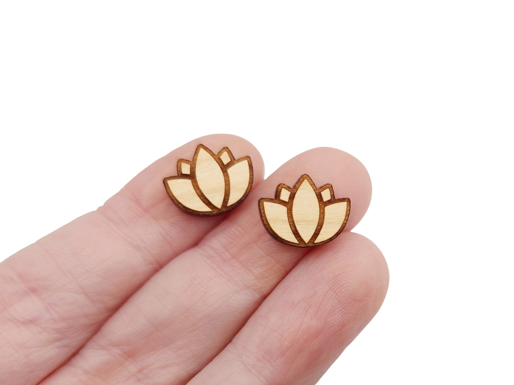 a hand holding a pair of wooden cabochon earring blanks cut and engraved to look like a lotus flower