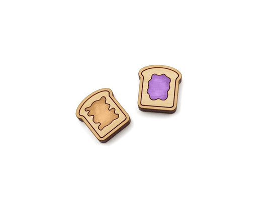 a pair of wooden cabochon stud earring blanks cut and engraved to look like pieces of bread with peanut butter and jelly