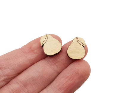 A hand holding a pair of wooden cabochon stud earring blanks cut and engraved to look like pears