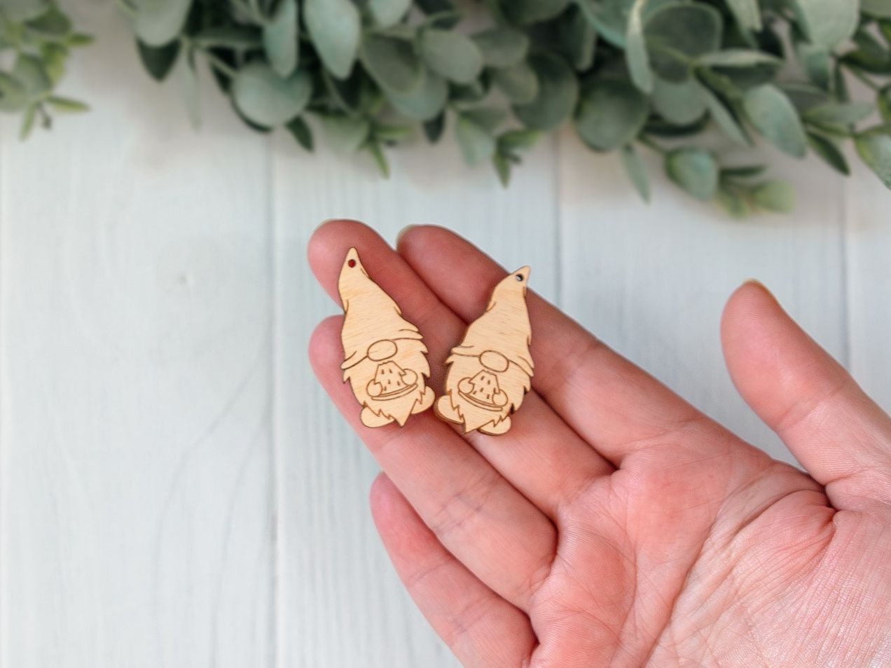 a hand holding a pair of wooden earrings