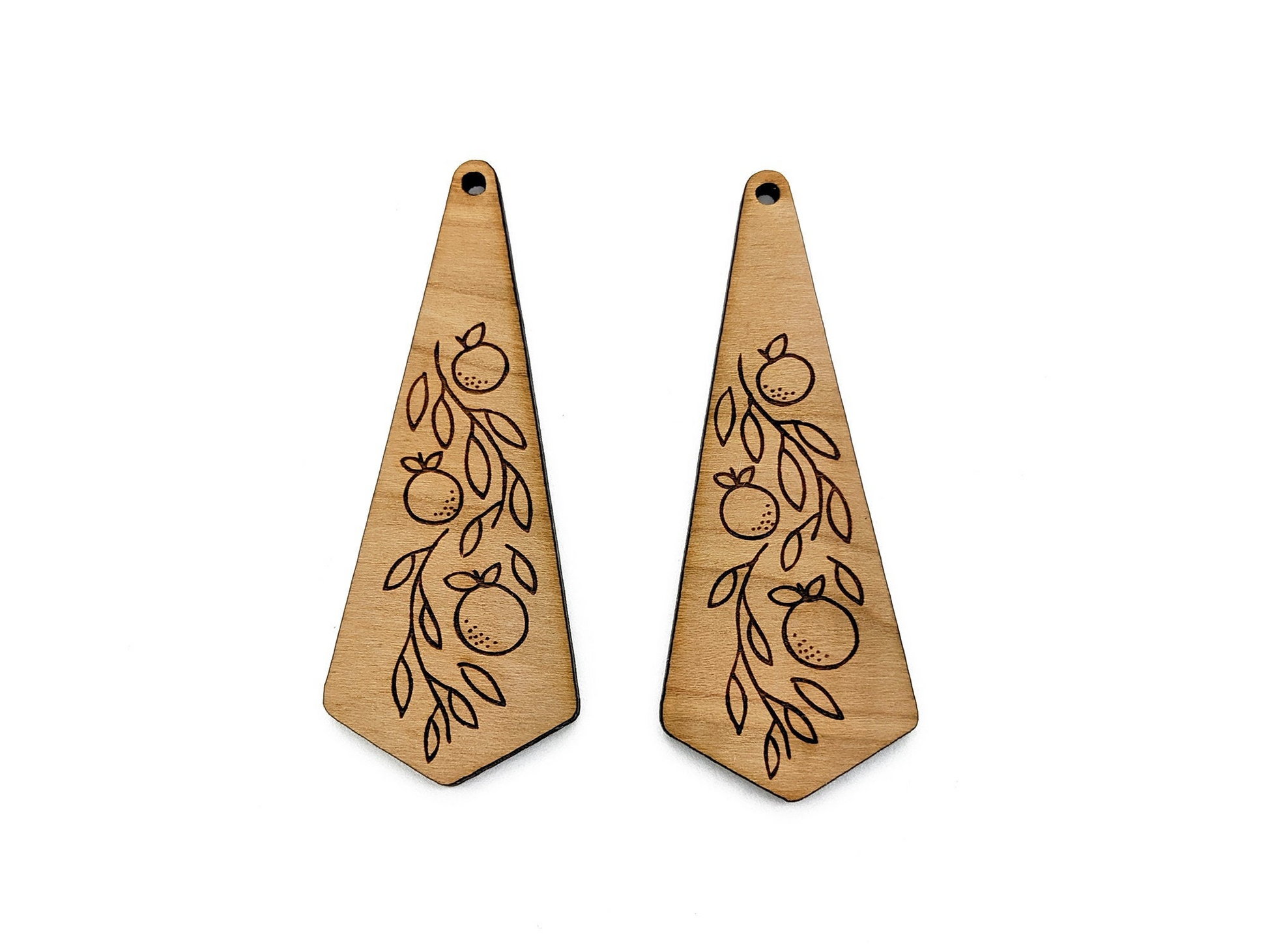 a pair of wooden earrings with fruit engraved on them