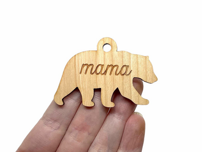 a hand holding a wooden ornament with the word mama on it