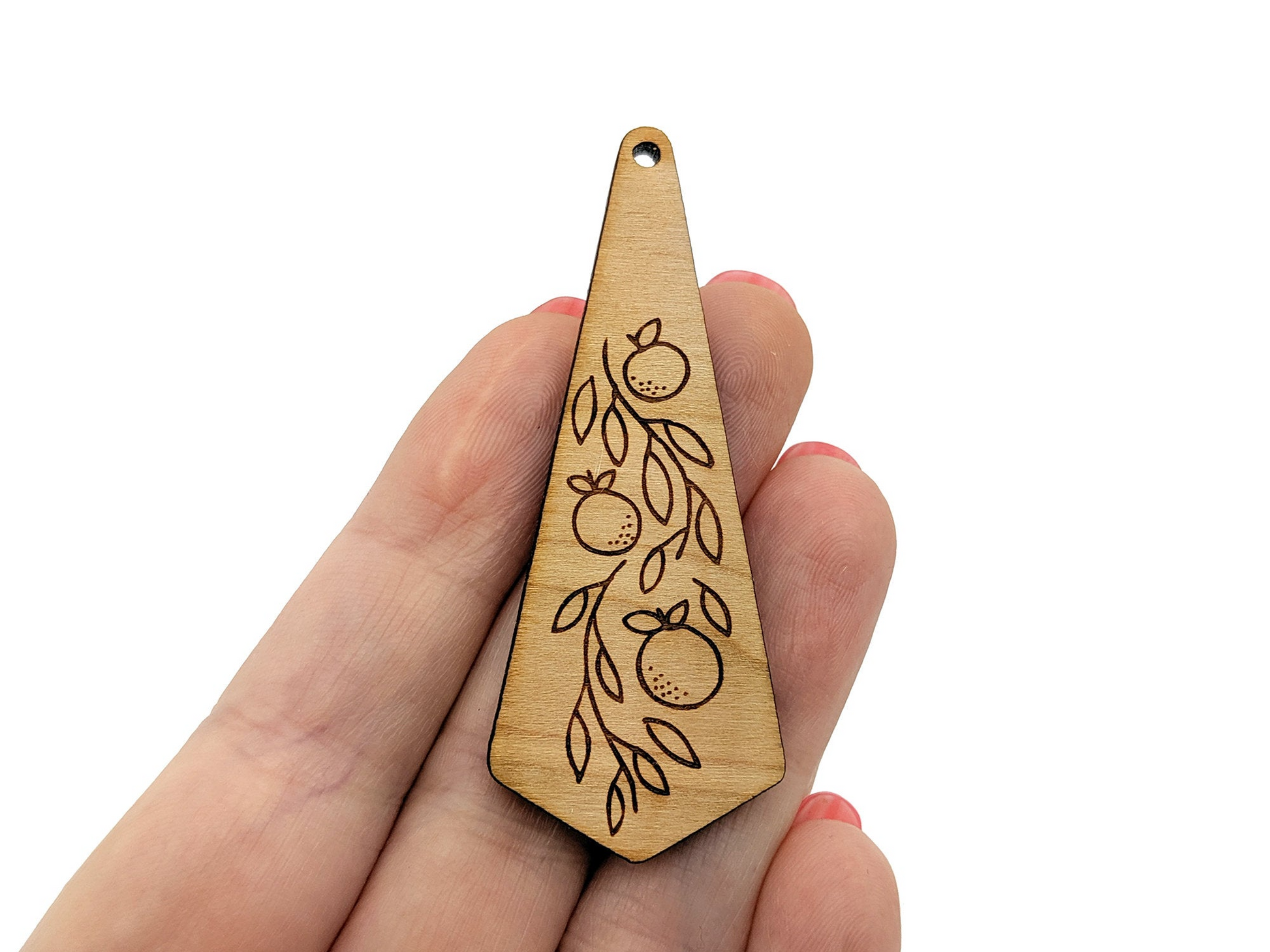 a hand holding a wooden ornament with a design on it