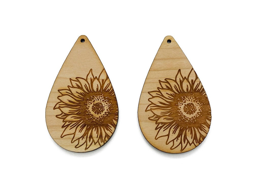 a pair of wooden earrings with a sunflower design