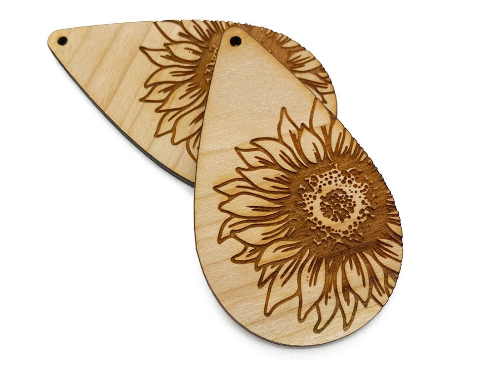 a pair of wooden earrings with a sunflower design