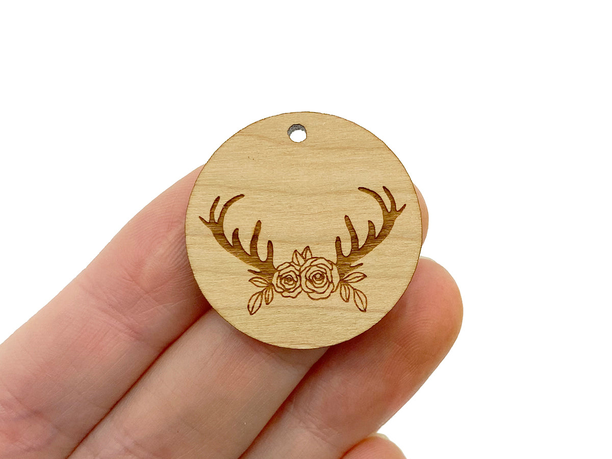 a hand holding a wooden ornament with deer antlers on it