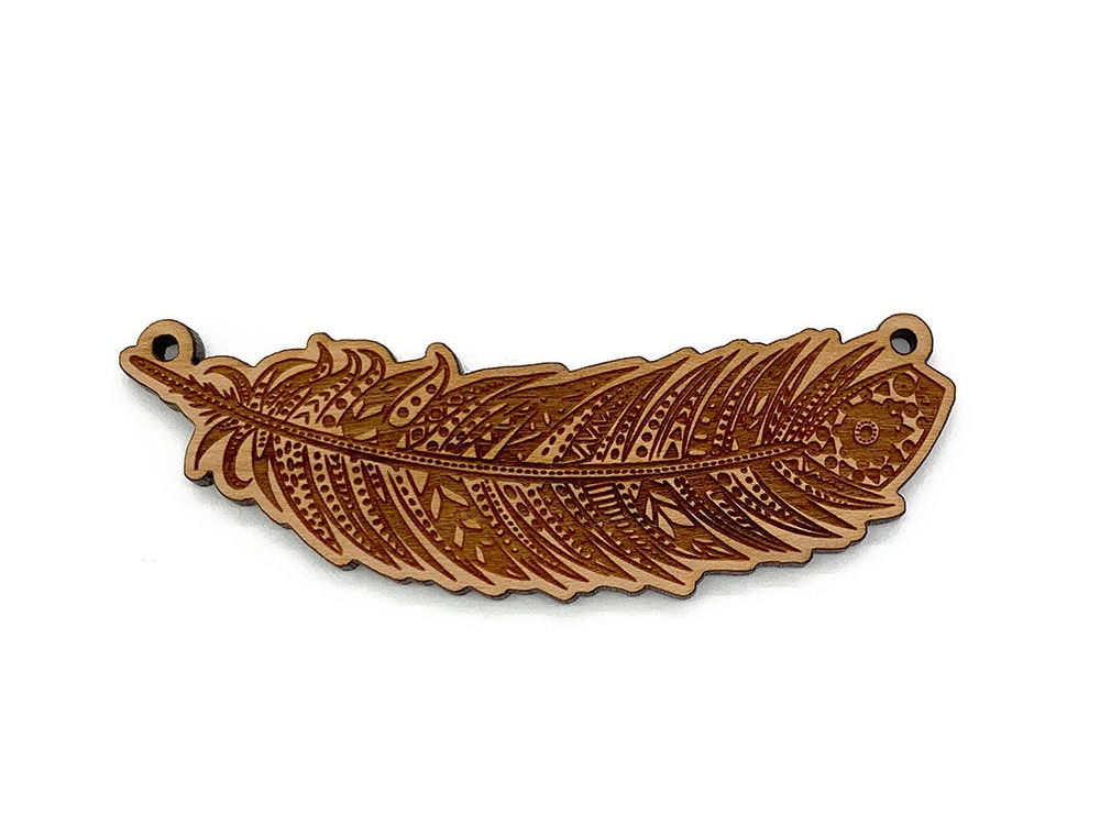 a wooden brooch with a brown feather on it