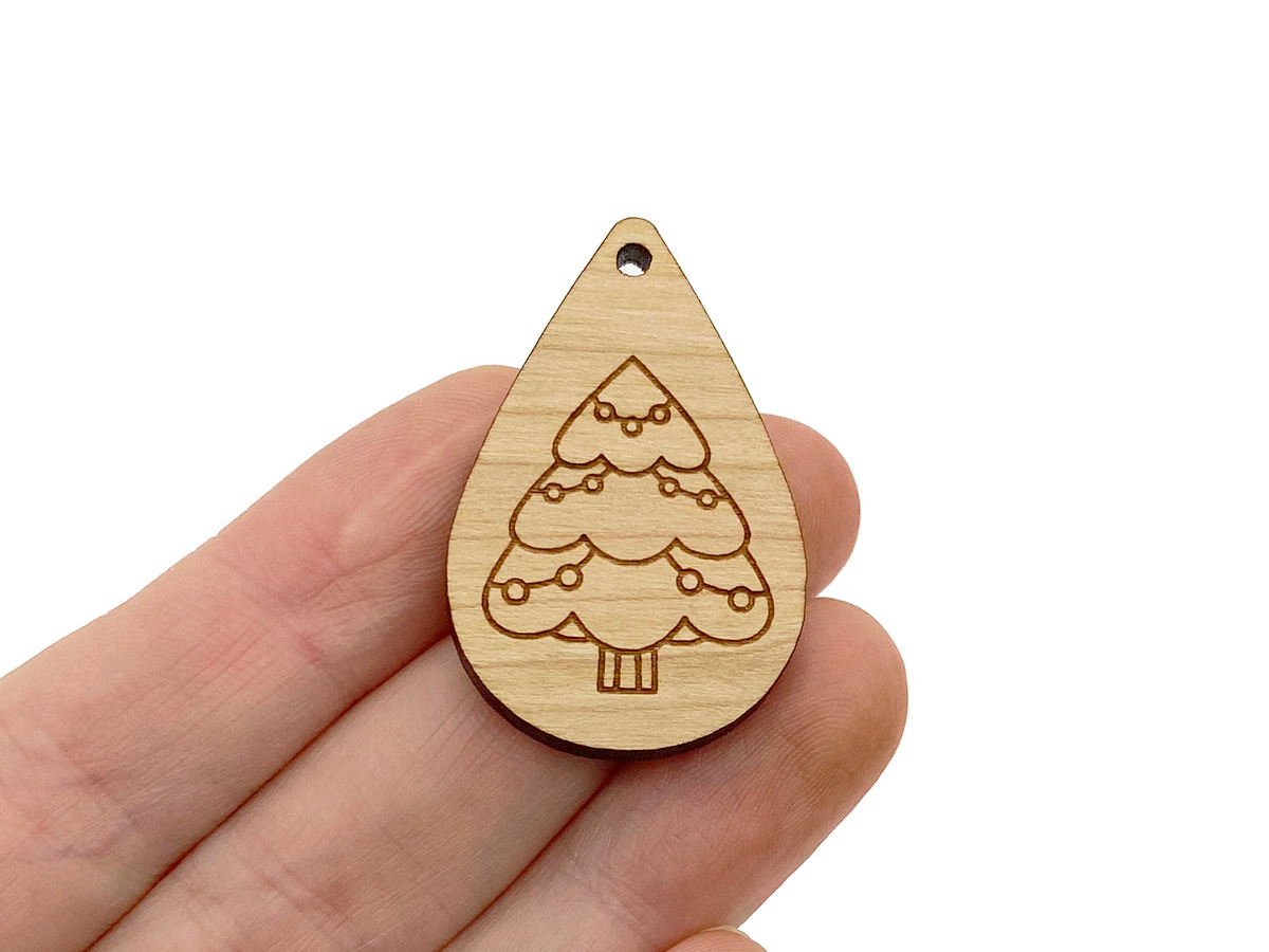 a hand holding a wooden ornament with a tree on it