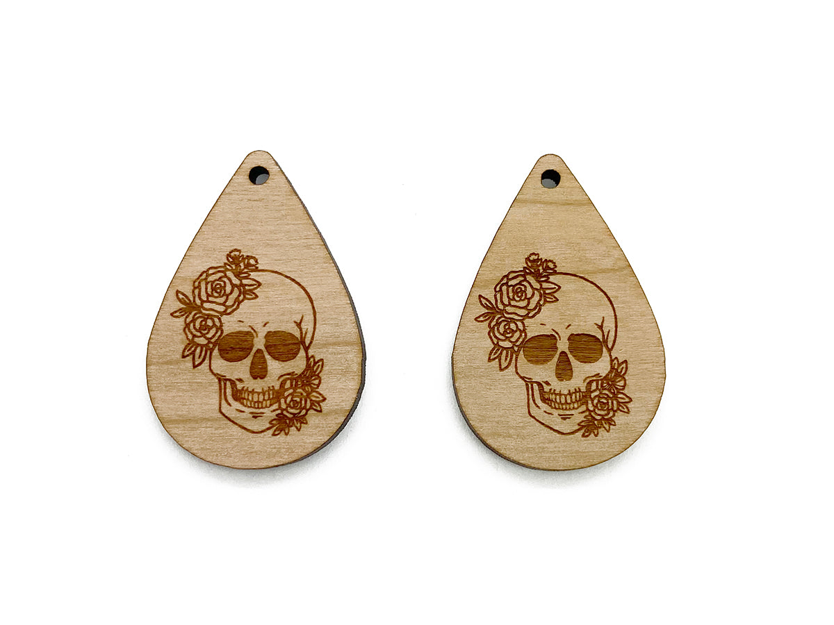 a pair of wooden earrings with a skull and roses on them