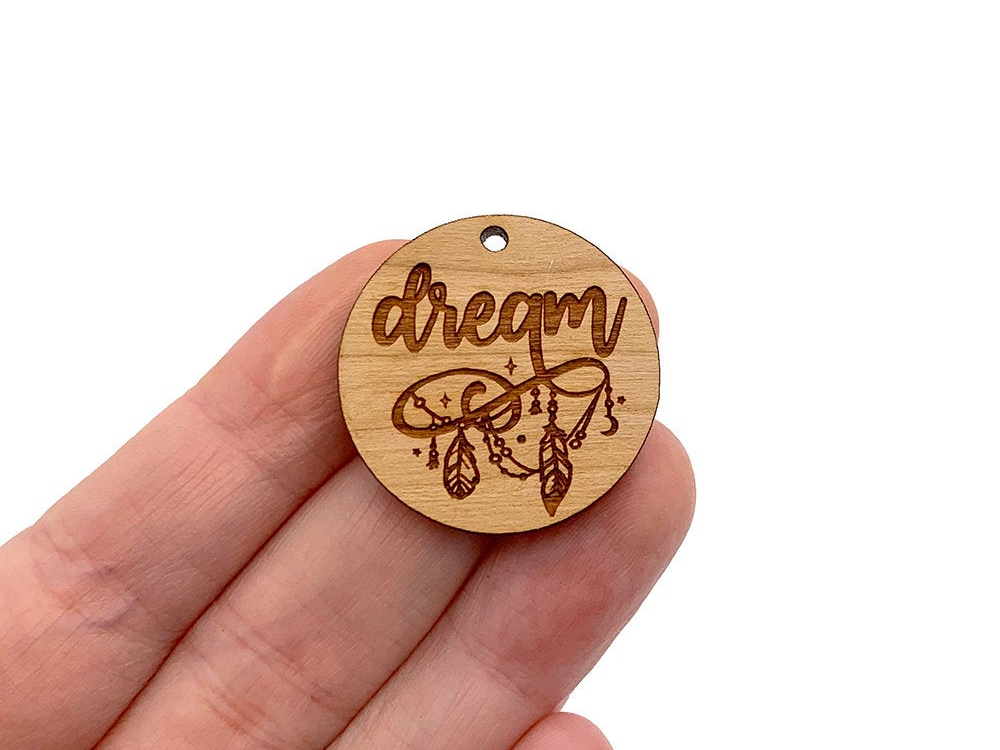 a hand holding a wooden charm that says dream
